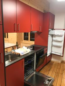 a kitchen with red cabinets and a sink and a refrigerator at Gite du pèlerin-Chalet de montagne in Orsières