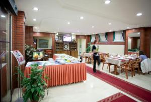 Eine Frau steht in einem Restaurant mit Tischen und Stühlen. in der Unterkunft SEFA HOTEL 1 ÇORLU in Çorlu