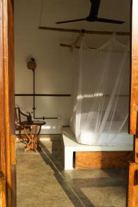 Habitación con cama y mesa con cortina en The Nuga House, en Ahangama
