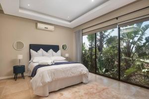 a bedroom with a large bed and a large window at 9 On Crystal Cove 5 Bedroom Townhouse in Zimbali in Ballito