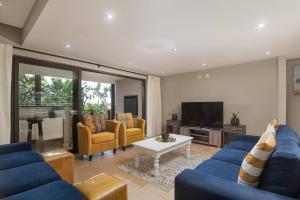 uma sala de estar com sofás azuis e uma televisão em 9 On Crystal Cove 5 Bedroom Townhouse in Zimbali em Ballito