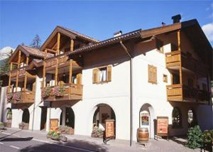 - un grand bâtiment blanc avec un balcon en bois dans l'établissement Residence Margherita, à Moena
