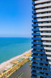 a tall building overlooking the beach and the ocean at Batumi Inn Aparthotel With Sea View in Batumi