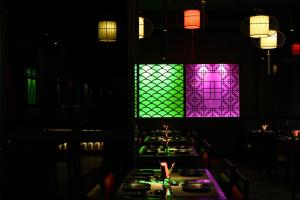 a restaurant with long tables with green and purple lights at Ashley Tang Menteng Jakarta in Jakarta