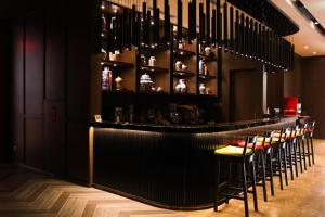 a bar with a row of stools in a room at Ashley Tang Menteng Jakarta in Jakarta