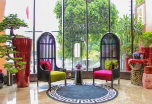 a room with two chairs and a window with plants at Ashley Tang Menteng Jakarta in Jakarta
