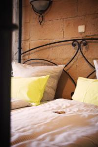 a bed with yellow and white pillows and a brick wall at Landhotel Zur Post in Bad König