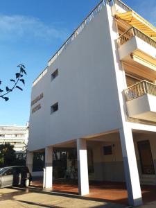 Un bâtiment blanc avec une voiture garée devant. dans l'établissement Hôtel Restaurant Brasilia, à Cagnes-sur-Mer