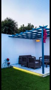 a patio with two benches and a blue umbrella at Altaraf Resort in Ash Shafa