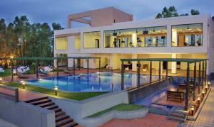 a large house with a swimming pool in front of it at Trinity Hotel Bengaluru in Bangalore