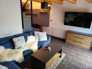 a living room with a blue couch and a tv at Privát Kras in Holštejn