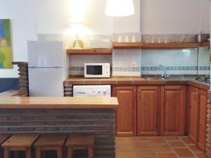 cocina con armarios de madera y nevera blanca en Apartamentos Turísticos La Mundial, en Málaga