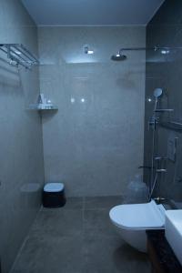 a bathroom with a shower and a toilet and a sink at Villa Grand Hotel Near Kempegowda International Airport in Bangalore