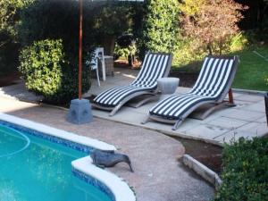 two lounge chairs sitting next to a swimming pool at La Belle Guest House in Bloemfontein