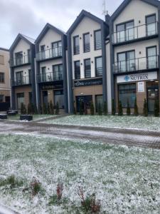 una fila de edificios de apartamentos con nieve en el suelo en Topaz Apartamenty en Augustów