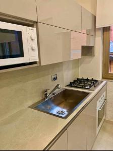 eine Küche mit einer Spüle und einer Mikrowelle in der Unterkunft Le Suite Abitare Roma in Rom