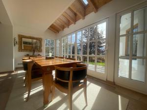 ein Esszimmer mit einem Holztisch, Stühlen und Fenstern in der Unterkunft Villa Kitzbühel in Kirchberg in Tirol