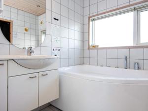 a white bathroom with a tub and a sink at 6 person holiday home in Ringk bing in Nørby