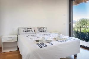 Schlafzimmer mit einem Bett mit weißer Bettwäsche und einem Fenster in der Unterkunft Villa Loncrino, First Floor Apartment in Torri del Benaco
