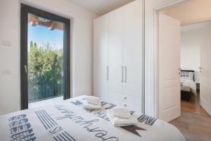 ein weißes Schlafzimmer mit einem großen Fenster und einem Bett in der Unterkunft Villa Loncrino, First Floor Apartment in Torri del Benaco