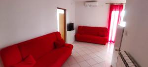 a red couch in a living room with a red chair at Apartmani Kevric in Novi Vinodolski
