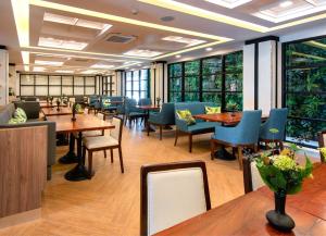 Sann Hotel في شيانج راي: مطعم بطاولات وكراسي ونوافذ
