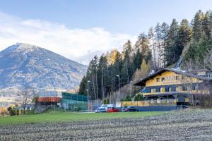 un bâtiment dans un champ avec une montagne en arrière-plan dans l'établissement The Art and Sporthotel, à Innsbruck