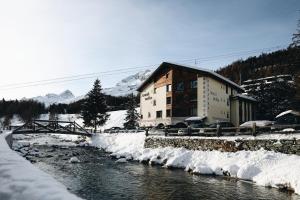 un edificio nella neve vicino a un fiume di Hotel Nolda a Sankt Moritz
