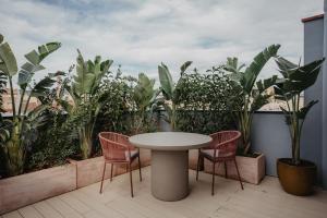 una mesa y sillas en un balcón con plantas en Petit Luxe Volta ÀTIC, en Terrassa