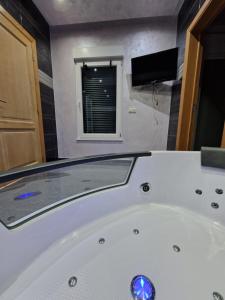 uma banheira branca na casa de banho com uma televisão em Tendresse - Espace Détente Ensival em Verviers