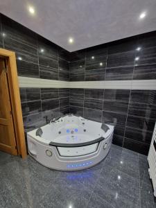 a jacuzzi tub in a bathroom with black tiles at Tendresse - Espace Détente Ensival in Verviers