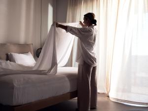 a woman standing next to a bed and talking on a phone at Cielo Luxury Villas in Zakynthos Town