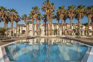 uma piscina com palmeiras em frente a um edifício em Porto Bello Beach Hotel em Kardamaina