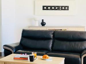a black leather couch sitting in a living room with a table at Canaryislandshost I Marquesa in Famara +36 photos