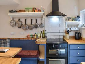 a kitchen with blue cabinets and a stove top oven at Vine Cottage in Crich
