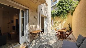 eine Terrasse mit einem Holztisch und Stühlen neben einem Gebäude in der Unterkunft Appartement maison Jeanne by Booking Guys in Nizza