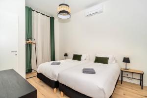 2 Betten in einem weißen Zimmer mit grünen Vorhängen in der Unterkunft LUXURY CONGRES in Nizza