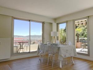 a dining room with a table and chairs and windows at Appartement 'Eucalyptus' in Nice