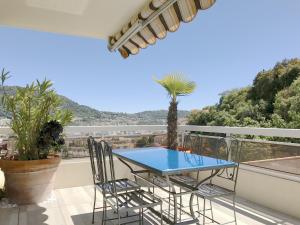 a blue table and chairs on a balcony with a palm tree at Appartement 'Eucalyptus' in Nice