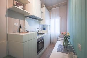 a small kitchen with white cabinets and a vase of flowers at Apartments Florence - Pinzochere White in Florence