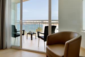 ein Wohnzimmer mit einem Stuhl und einem Balkon in der Unterkunft Palladium Hotel Palmyra - Adults Only in Sant Antoni de Portmany