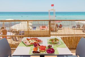 stół z dwoma talerzami jedzenia na plaży w obiekcie Costa del Salento - CDSHotels w mieście Lido Marini