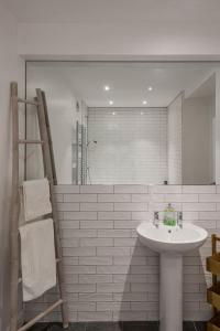 y baño blanco con lavabo y ducha. en Nelson Crescent East : Modern one bedroom basement apartment in central location, en Kent