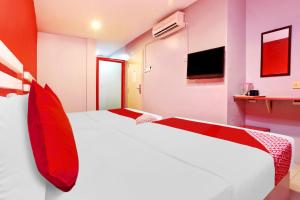 a bedroom with two beds with red pillows and a tv at OYO 89654 My New Home Hotel in Gua Musang