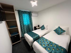 two beds in a room with blue curtains at HOTEL DE LA PAIX Lyon Sud Givors in Givors