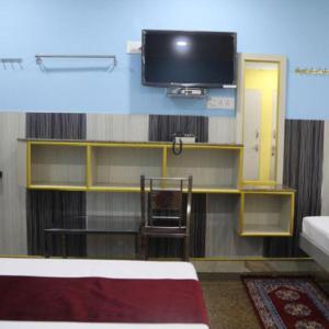 a room with a flat screen tv and a chair at Chakravarthy Holidays in Kanchipuram +16 photos