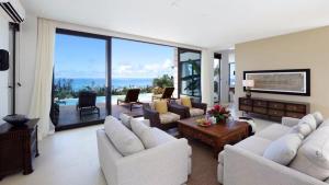 una sala de estar con muebles blancos y vistas al océano. en Navy Hill Resort en Garapan