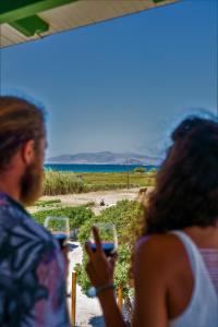 dos personas mirando sus celulares en la playa en Studios Vrettos Beachfront Hotel, en Plaka