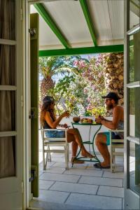 two people sitting at a table on a porch at Studios Vrettos Beachfront Hotel in Plaka