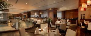 a restaurant with white tables and chairs and a bar at Fortune Select Exotica, Navi Mumbai - Member ITC's Hotel Group in Navi Mumbai